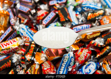 Einen Löffel Zucker mit einer Auswahl an Pralinen aus der Dose von feiern. Stockfoto