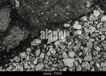 Groben Kies trifft glatten Asphalt in schwarz und weiß - mit Diagonale Komposition, markieren Sie die verschiedenen Formen und Arten von Stockfoto