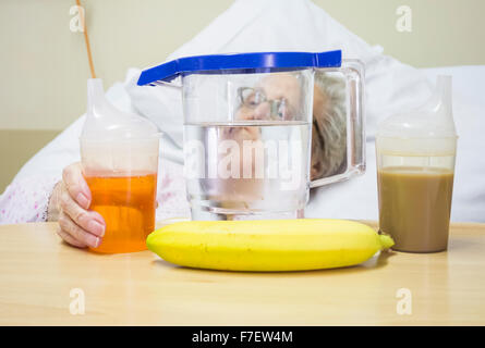 Neunzig Jahre alte Patientin im NHS Krankenhaus mit Wasser, Tee und Limonade auf Nachttisch Stockfoto