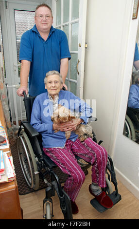 Männliche Pflegekraft schieben eine ältere Frau in einem Rollstuhl (Mutter & Sohn sein könnte) Stockfoto