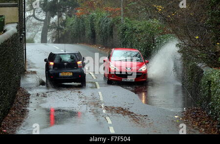 Swansea UK. Montag, 30. November 2015 rot Peugeot Auto fährt durch eine Wasserpfütze im Süden Brynmill Lane, Swansea, Wales, als starke Winde und schwere Regen hat Auswirkungen auf die meisten Teile auf das Vereinigte Königreich. Bildnachweis: D Legakis/Alamy Live-Nachrichten Stockfoto