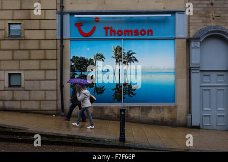 Huddersfield, UK. 30. November 2015. Eine Frau zu Fuß vorbei an einem Plakat in einem Thomson Travel Agents zeigt eine Sonne verwöhnten Insel mit Palmen. Bildnachweis: West Yorkshire Bilder/Alamy Live-Nachrichten Stockfoto