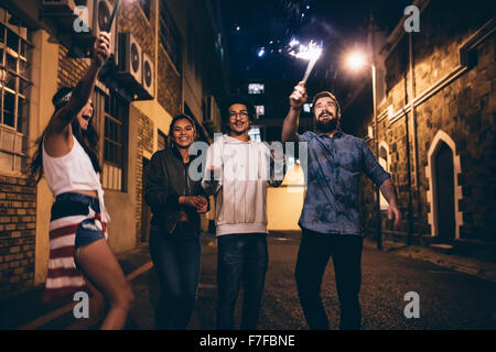 Schuss ein junger Menschen spielen mit Wunderkerzen in der Nacht. Beste Freunde hanging out in der Nacht und 4. Juli im Freien zu feiern. Stockfoto