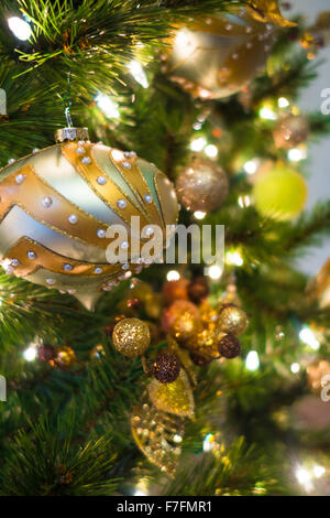 Schöne Weihnachten Ornamente werden an eine elegante Weihnachtsbaum mit weißen Lampen aufgehängt. Stockfoto