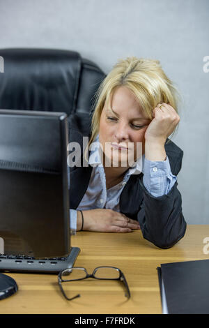 Eine weibliche Büroangestellte sitzt an ihrem Schreibtisch auf ihren 9-5 job Stockfoto