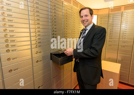 Ein Bankangestellter steht in einem Tresorraum und öffnet eine Loge. Stockfoto