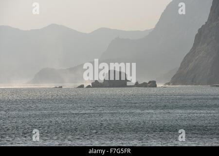 Malerische Aussicht von Sudak in Richtung neue Welt Position mit Fahne von Spray, ausgelöst durch den stürmischen Wind über Meerwasser im Sonnenlicht über Cr Stockfoto