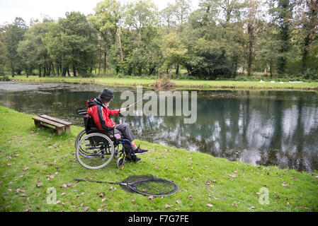 Ein behinderter Mensch fischt aus seinem Rollstuhl Stockfoto