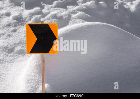Eine orange und schwarz Trail Zeiger Zeichen in ein Snowbank stecken. Stockfoto