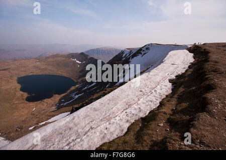 Auf dem Gipfel des Helvellyn in Lake District National Park. Ein Schnee Gesims klammert sich an den Rand des Gipfels. Stockfoto