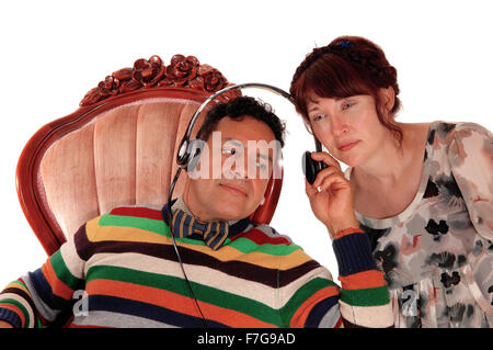 Einen mittleren Alters Hispanic Mann sitzt in einem Sessel mit Kopfhörer, Musik zu hören und seine Frau hören auch isoliert für Pfingstmontag Stockfoto