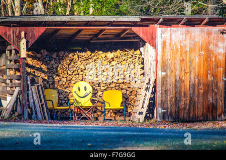 Panorama von einem Holzschuppen in New Hampshire, USA mit drei gelbe Stühle innen, hat man ein glückliches Gesicht Emoji auf seinen Rücken gemalt. Stockfoto