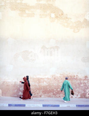 Marokkanische muslimische Männer gehen zügig vorbei an der Stadtmauer auf seinem Weg zum Morgengebet. Essaouira, Marokko Stockfoto