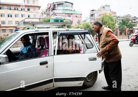 ein Mann mittleren Alters im Gespräch mit einer Frau mittleren Alters in ein Taxi auf der Straße der New Road, Kathmandu, 2015 Stockfoto
