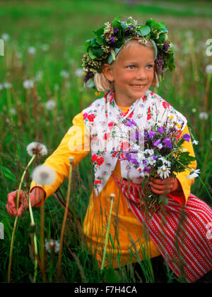 Mädchen in Tracht Mittsommer Kommissionierung Wildblumen für Kopf Kronen und Maibaum in Schweden Stockfoto