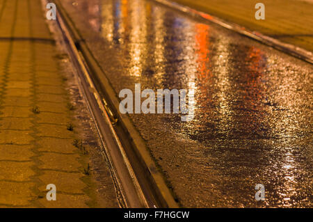 Nahaufnahme mit Straßenbahn Schiene nachts Lichter reflektiert in den nassen asphalt Stockfoto