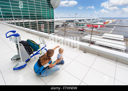 Junge Mutter und Baby Boy warten auf boarding, Flug im Flughafen-Transit-Halle und Blick auf Flugzeug in der Nähe von Abflug-gate Stockfoto