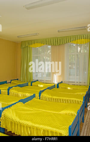 Reihen von Betten im Kindergarten gelbe Schlafzimmer Stockfoto