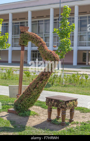 grüne Formschnitt Statue einer Harfe mit Hocker Stockfoto