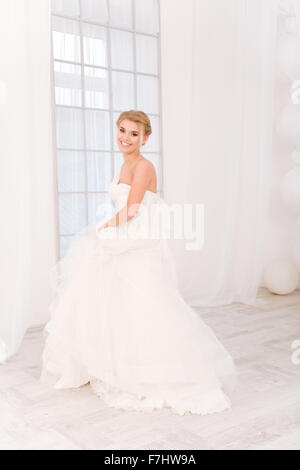 Porträt einer lächelnden Braut im weißen Hochzeitskleid und Blick in die Kamera Stockfoto