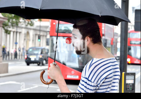 London, England, Vereinigtes Königreich. Clown mit einem Regenschirm in Parliament Square Stockfoto