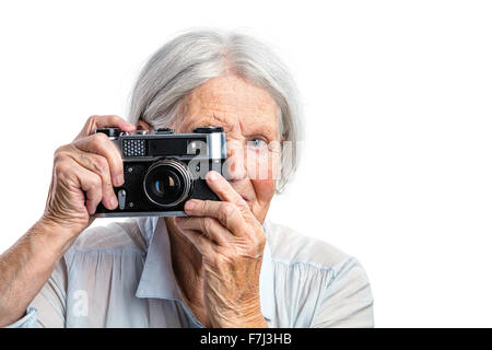 Senior woman shooting with a retro camera over white background Stockfoto
