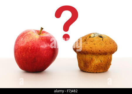 Rosy Red Apple und einen Muffin Kuchen auf einer Tischplatte mit einem Fragezeichen zwischen gesunden und ungesunden Essen Optionen Konzept zu veranschaulichen Stockfoto