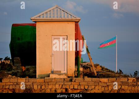 Aserbaidschanische Flagge vor und passenden Farben von Himmel, Hütte und Wassertank Stockfoto