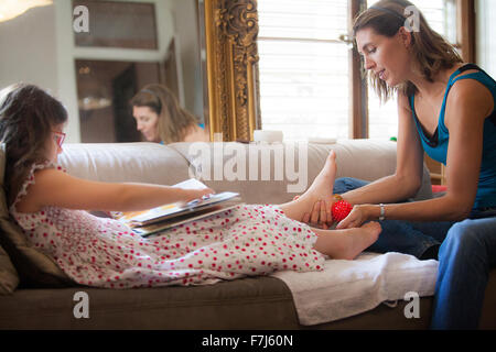 Reportage über Fußreflexzonenmassage für Kinder. Die Reflexologin befasst sich mit Kindern im Alter von 5 aufwärts. Reflexzonenmassage wirkt auf ihre Konzentration, Gedächtnis, Balance, Ruhe und Schlaf. Ein 7 - Jahre altes Mädchen in einer Sitzung. Stockfoto