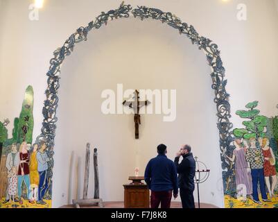 Bernburg, Deutschland. 30. November 2015. Kirche Pfarrer Sven Baier (R) und ein Mann untersuchen Emailplatten 30. November 2015 von Grafiker und Maler Moritz Goetze (nicht im Bild) in der Apsis der Schlosskirche St. Aegidien in Bernburg, Deutschland, gefertigt. Die Platte gehört zu einem Zyklus von Kunstwerken, die Szenen aus der Bibel in die heutige Zeit transportiert. Goetze arbeitet auf der Serie von Kunstwerken für die vergangenen drei Jahre rund 320 einzelne Emailplatten basteln. Foto: Waltraud Grubitzsch/Dpa/Alamy Live News Stockfoto