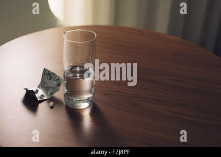 Glas Wasser und Blisterpackung der Medizin auf Tisch Stockfoto