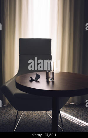 Glas Wasser und Medikamente auf Tisch im Hotelzimmer Stockfoto