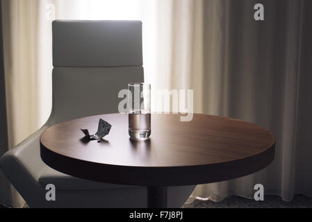 Glas Wasser und Medikamente auf Tisch im Hotelzimmer Stockfoto