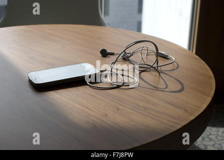 Smartphone und Ohrhörer auf Tisch Stockfoto