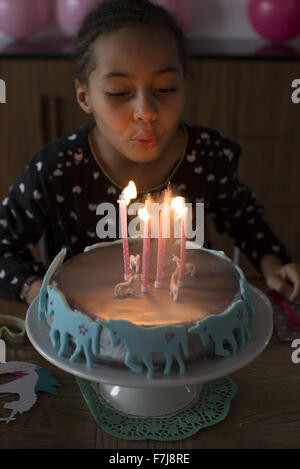 Mädchen bläst Kerzen auf Geburtstagskuchen Stockfoto