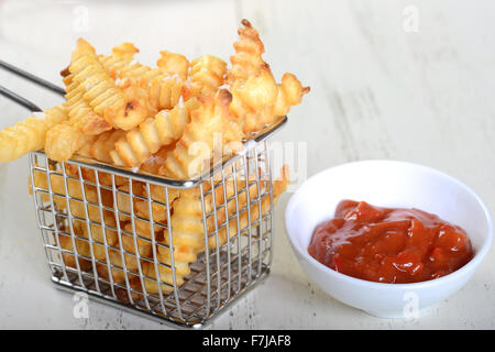 Knusprige Pommes frites in einen Drahtkorb für die Friteuse mit einem würzigen roten Pfeffer aoli Stockfoto