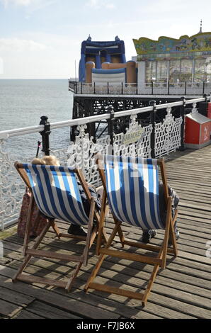 Ein älteres Ehepaar in Liegestühlen am Pier von Brighton in East Sussex Stockfoto