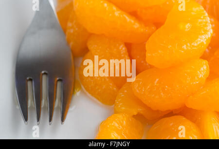 Nahaufnahme einer Portion Dose Mandarin-Orangen auf einem weißen Teller mit einer Gabel zur Seite. Stockfoto