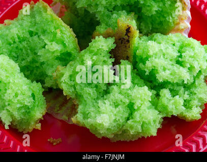 Nahaufnahme von einem frisch gebackenen Pistazien Frühstück Muffin, der auf einem roten Plastikteller in mehrere Teile aufgeteilt wurde. Stockfoto