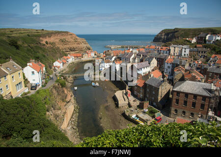 Sonnigen Blick auf malerische Staithes, North Yorkshire, GB, UK - malerische Fischerdorf mit zusammengekauert auf dem Land, Naturhafen und blauer Himmel. Stockfoto