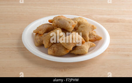 Eine Portion Biss Größe Pizza rollt auf einem weißen Schaum Teller oben auf einer hölzernen Tischplatte mit natürlichem Licht beleuchtet. Stockfoto