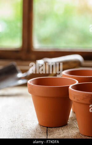 Drei Terrakotta-Töpfe auf einem Pottingbank mit Hand Kelle im Hintergrund. Stockfoto