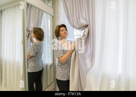 Frau für Vorhänge hängen im Fenster Stockfoto