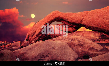 Lila Sonnenuntergang und aufgehenden Mond über Bogen in Joshua Tree Nationalpark, Kalifornien, USA. Stockfoto