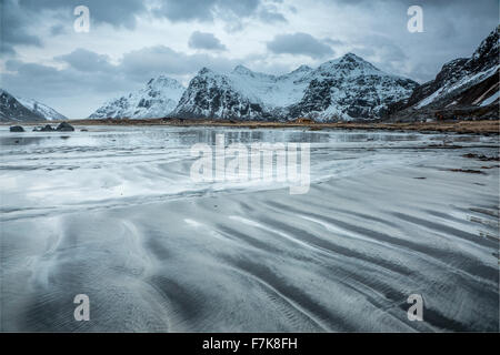 Schneebedeckte Berge hinter kalten, Skagsanden Strand, Lofoten Inseln, Norwegen Stockfoto