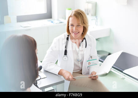 Arzt mit medizinischen Diagramm im Gespräch mit Patienten im Untersuchungsraum Stockfoto