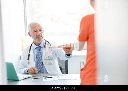 Arzt am Schalter geben Krankenakte in Arztpraxis Krankenschwester Stockfoto