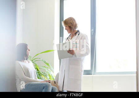 Arzt mit medizinischen Aufzeichnungen im Gespräch mit Patienten im Wartezimmer Stockfoto