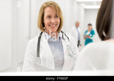 Arzt im Gespräch mit Patienten im Krankenhausflur lächelnd Stockfoto