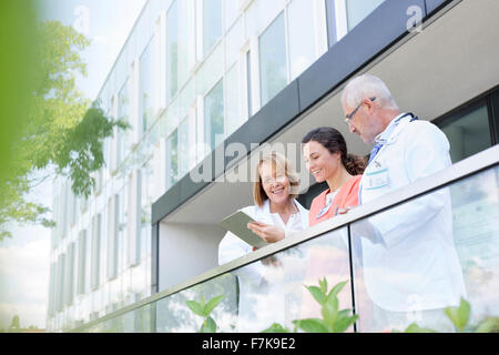 Ärzte und Krankenschwester Überprüfung Krankenakte auf Krankenhaus-Balkon Stockfoto